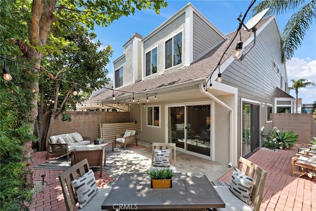 rear view of house with a shingled roof, outdoor lounge area, a patio area, and fence