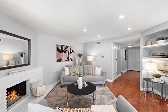 living room featuring a fireplace, recessed lighting, wood finished floors, and visible vents