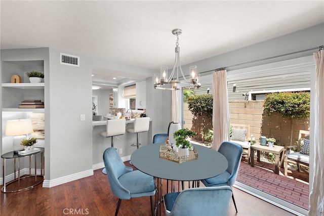 dining area featuring baseboards, visible vents, an inviting chandelier, and wood finished floors