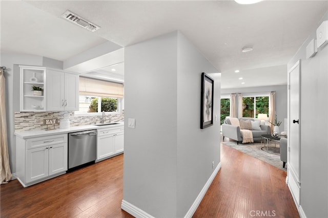 hall featuring visible vents, wood finished floors, baseboards, recessed lighting, and a sink