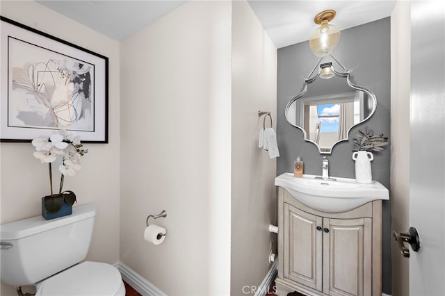 bathroom with toilet, baseboards, and vanity