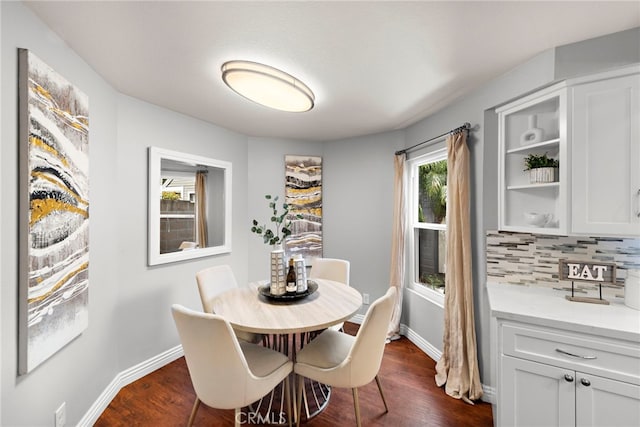 dining room with dark wood-type flooring, baseboards, and a healthy amount of sunlight