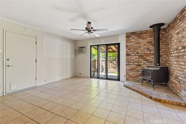 unfurnished living room with a wood stove, brick wall, ceiling fan, an AC wall unit, and light tile patterned floors