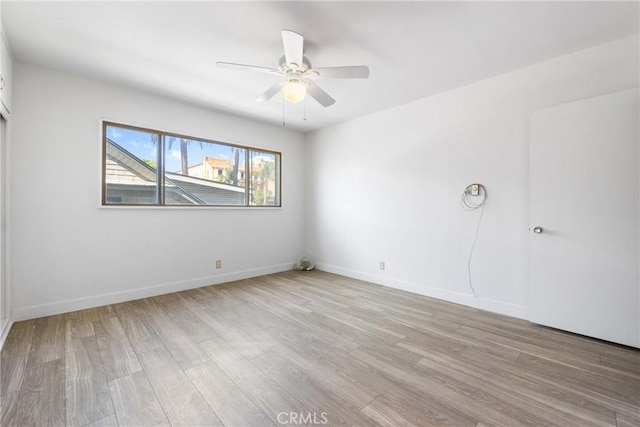 empty room with a ceiling fan, baseboards, and light wood-type flooring