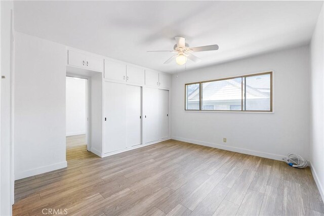 unfurnished bedroom featuring light wood-style floors, baseboards, a ceiling fan, and a closet