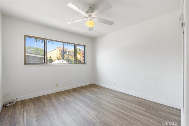 empty room with baseboards, ceiling fan, and light wood-type flooring
