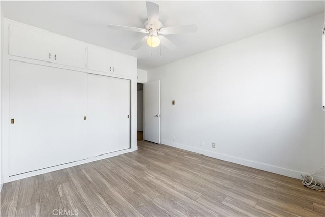 unfurnished bedroom featuring a closet, a ceiling fan, light wood-style flooring, and baseboards