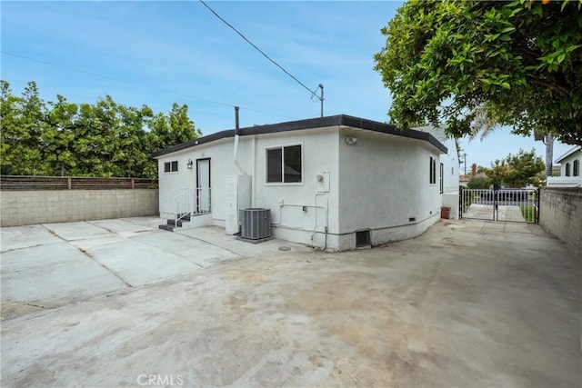 rear view of property featuring a patio area, central air condition unit, a fenced backyard, entry steps, and stucco siding