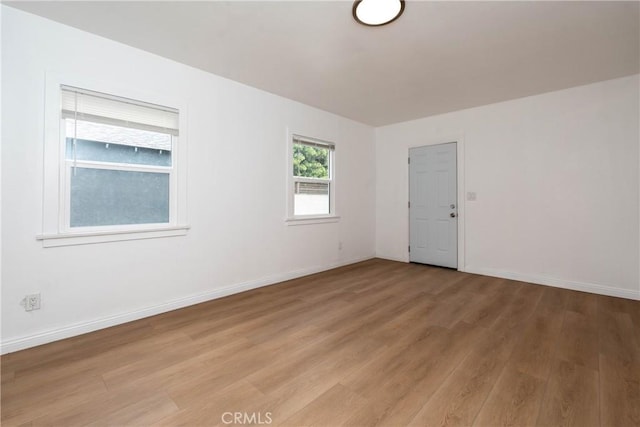 unfurnished room with baseboards and light wood-type flooring