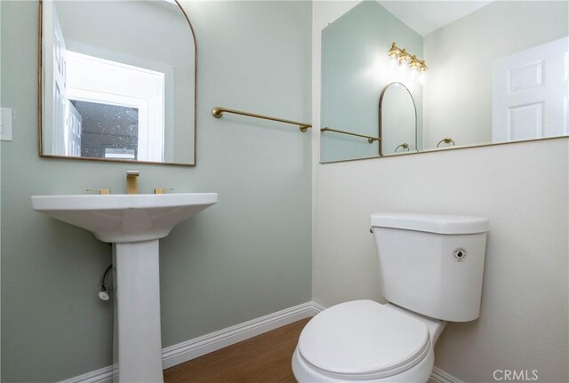 bathroom with toilet, baseboards, and wood finished floors