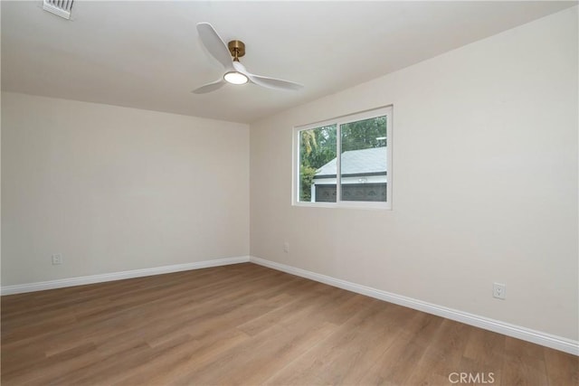 empty room featuring light wood-style floors, baseboards, ceiling fan, and visible vents