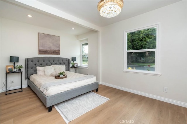 bedroom with baseboards, recessed lighting, light wood-style flooring, and a notable chandelier
