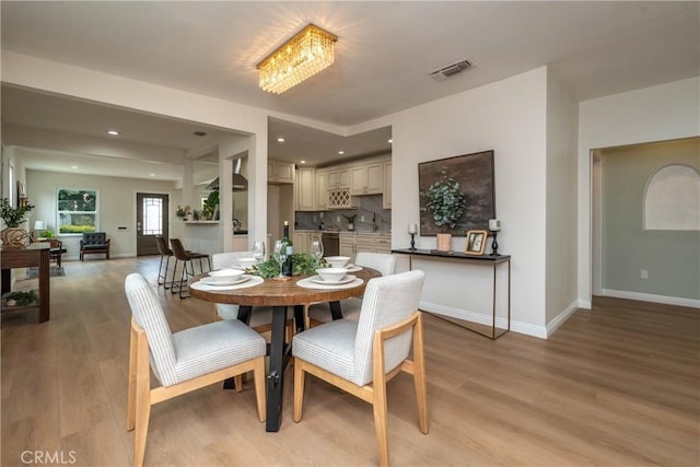 dining space featuring baseboards, visible vents, and light wood-style floors