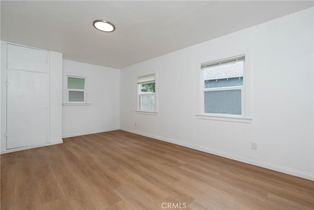 unfurnished room with baseboards and light wood finished floors