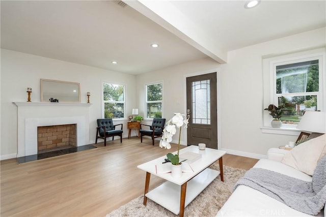 living room featuring a fireplace with flush hearth, baseboards, recessed lighting, and light wood-style flooring