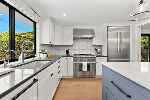 9401 Gateshead Dr, Huntington Beach, CA 92646 - kitchen featuring high end appliances, wall chimney range hood, recessed lighting, tasteful backsplash, and a sink
