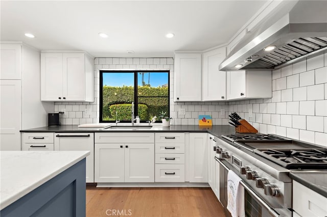 9401 Gateshead Dr, Huntington Beach, CA 92646 - kitchen featuring white cabinets, a sink, wall chimney exhaust hood, high end range, and decorative backsplash