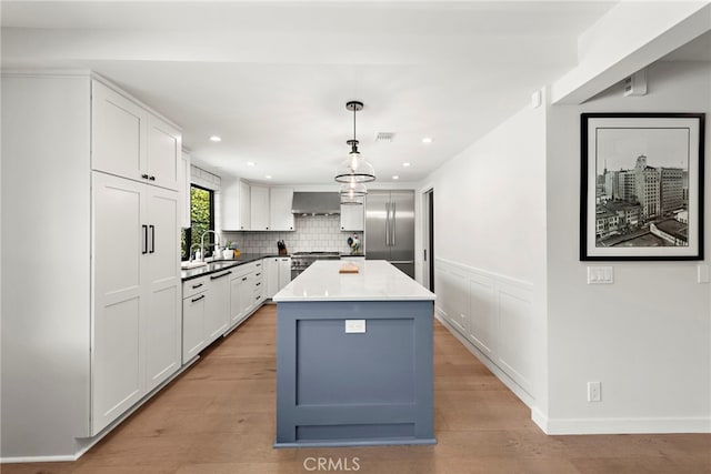 9401 Gateshead Dr, Huntington Beach, CA 92646 - kitchen featuring white cabinetry, premium appliances, light wood finished floors, and wall chimney exhaust hood