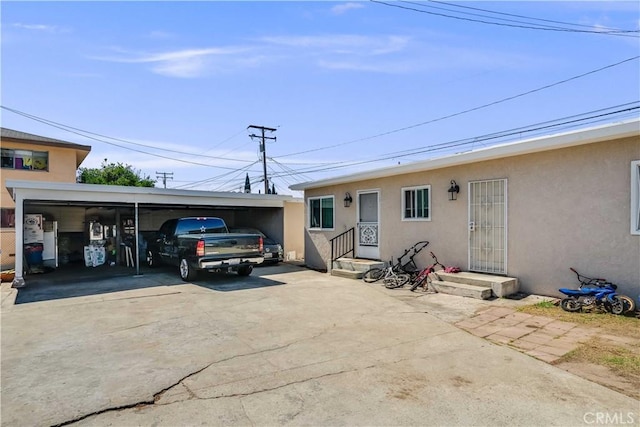view of front facade with stucco siding, driveway, and a carport