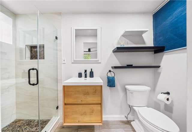 full bath featuring a shower stall, wood finished floors, toilet, vanity, and baseboards