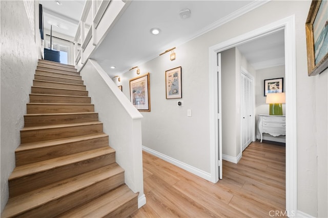 stairway featuring wood finished floors, baseboards, crown molding, and recessed lighting