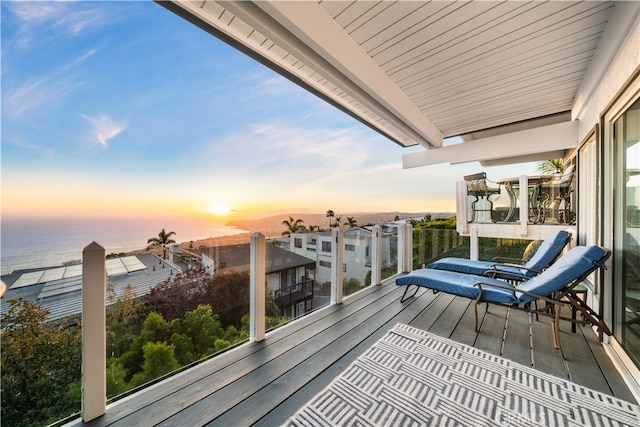 balcony at dusk featuring a water view
