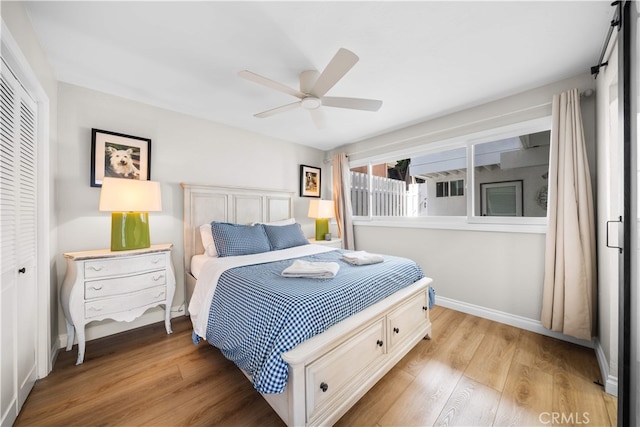 bedroom with a closet, light wood-style floors, baseboards, and ceiling fan