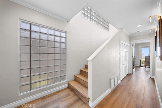 stairs with crown molding, wood finished floors, baseboards, and recessed lighting