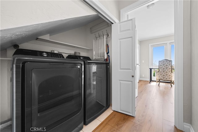 washroom with independent washer and dryer, light wood finished floors, and baseboards