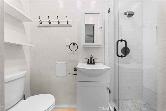 bathroom featuring toilet, a shower stall, and vanity