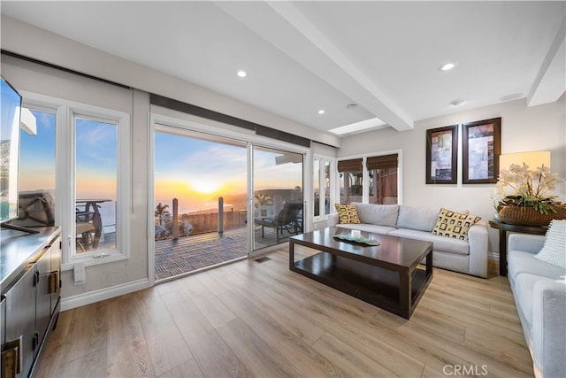 living room featuring beamed ceiling, light wood-type flooring, recessed lighting, and baseboards