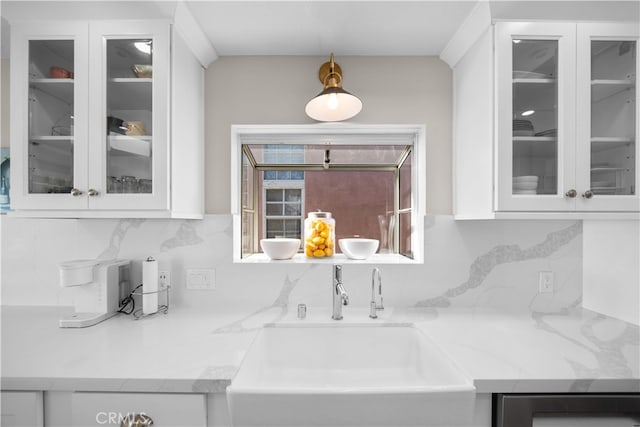 kitchen featuring a sink, white cabinetry, backsplash, glass insert cabinets, and decorative light fixtures