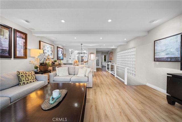 living area featuring beam ceiling, light wood finished floors, baseboards, recessed lighting, and a chandelier