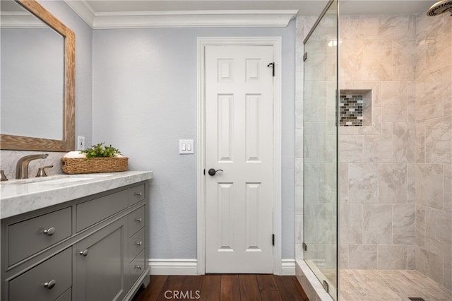 full bath with vanity, baseboards, a shower stall, wood finished floors, and ornamental molding