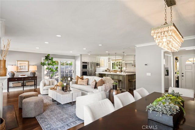 living room with recessed lighting, dark wood-style flooring, crown molding, and a chandelier