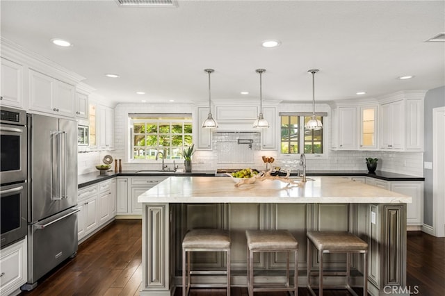 kitchen with a sink, appliances with stainless steel finishes, white cabinets, and dark wood-style floors