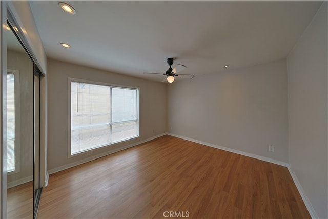 empty room with baseboards, recessed lighting, ceiling fan, and wood finished floors