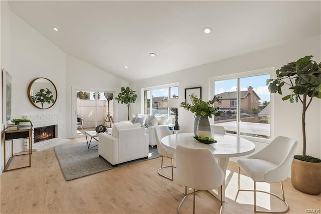 8892 Katella Ave Unit 12, Anaheim, CA 92804 - dining space featuring light wood finished floors, a brick fireplace, recessed lighting, and high vaulted ceiling