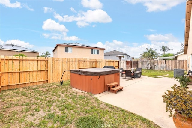 exterior space with a fenced backyard, a hot tub, a patio area, and central AC