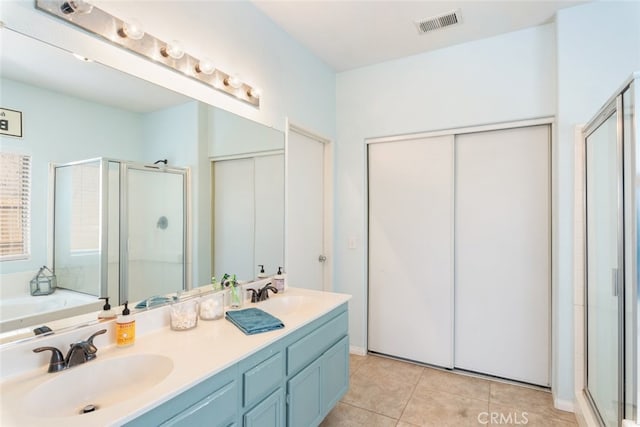 full bath with a sink, tile patterned floors, a shower stall, and double vanity