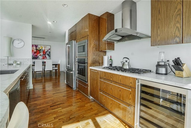 3141 Michelson Dr Unit 508, Irvine, CA 92612 - kitchen with wall chimney exhaust hood, stainless steel appliances, wine cooler, wood finished floors, and brown cabinetry