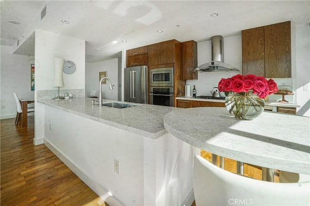3141 Michelson Dr Unit 508, Irvine, CA 92612 - kitchen with wall chimney exhaust hood, appliances with stainless steel finishes, a sink, wood finished floors, and a peninsula