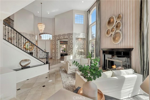 living room featuring a glass covered fireplace, a high ceiling, stairs, and a wealth of natural light
