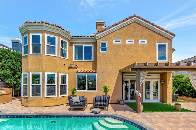 back of property with french doors, stucco siding, a patio area, and a tile roof