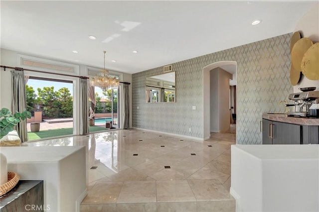 interior space featuring arched walkways, a chandelier, recessed lighting, baseboards, and visible vents