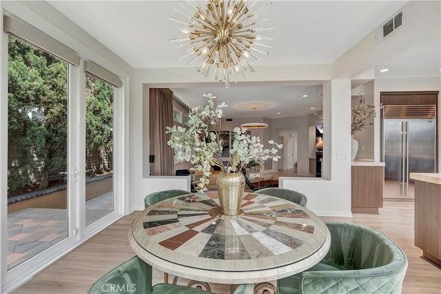 dining space with visible vents, a chandelier, and light wood-type flooring
