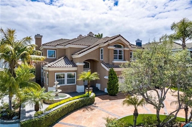 mediterranean / spanish-style home featuring stucco siding, a chimney, and a tile roof