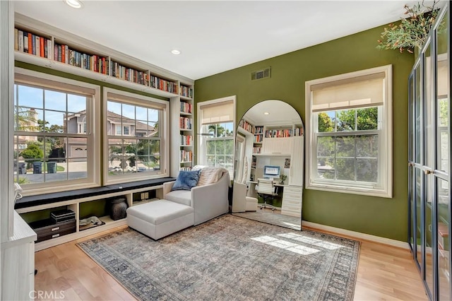 sitting room featuring baseboards, a wealth of natural light, wood finished floors, and visible vents
