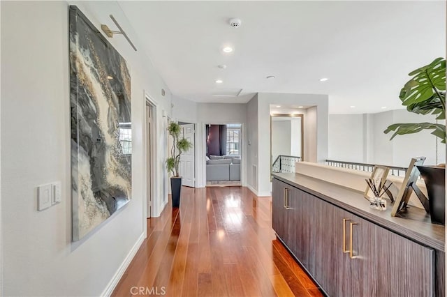 corridor featuring baseboards, recessed lighting, and wood finished floors