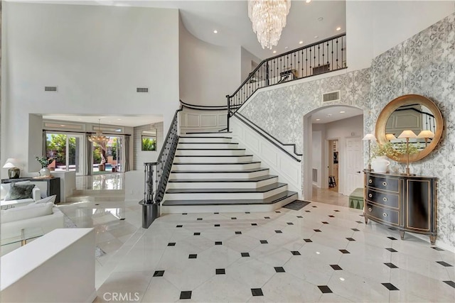 foyer entrance featuring light tile patterned flooring, a high ceiling, a notable chandelier, and stairway